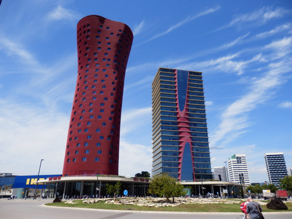 Hotel-Türme von Toyo Ito, rund-verformt in rot links, rotes gegabeltes Element vor grauer Fassade rechts